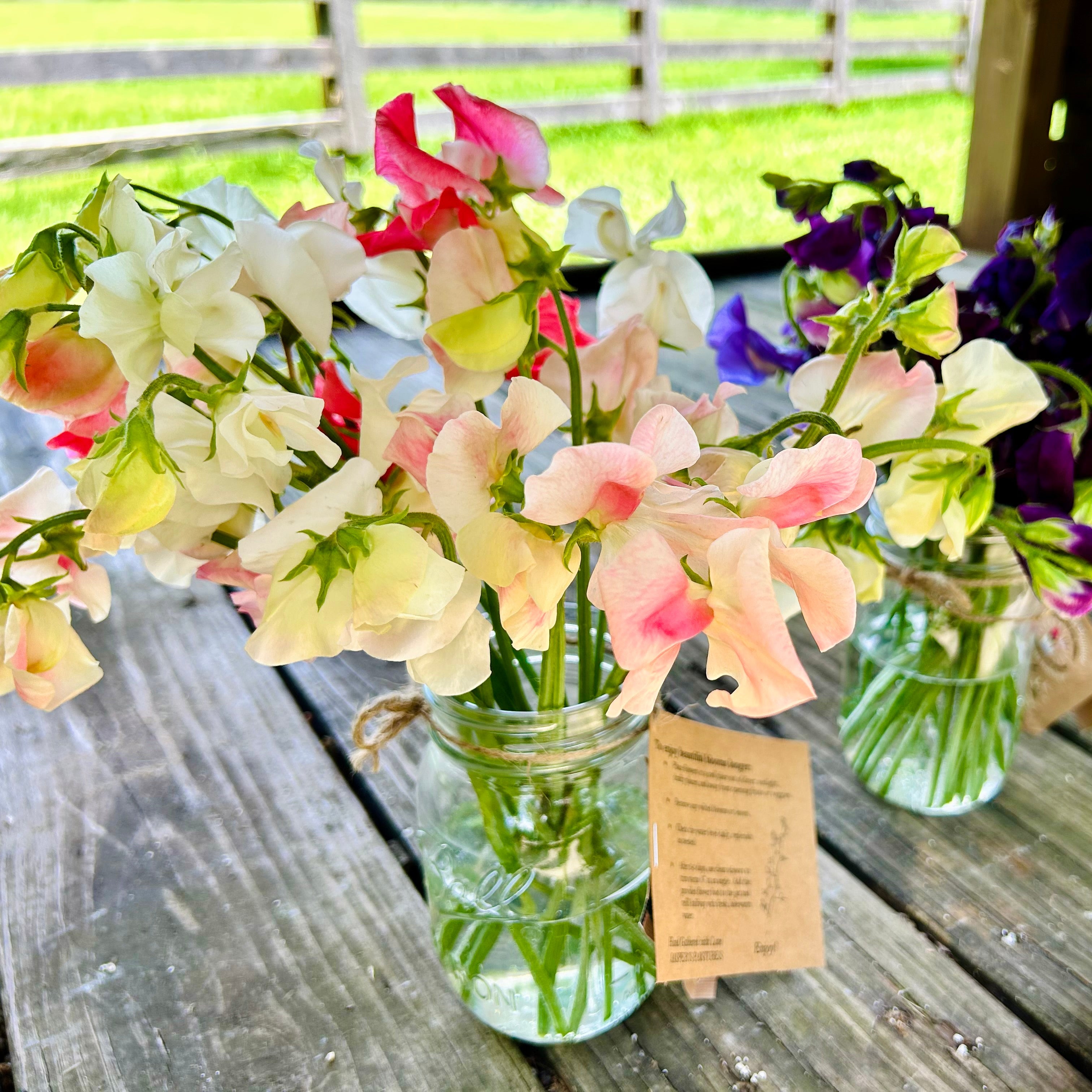 Vases with flowers on a wooden table outdoors