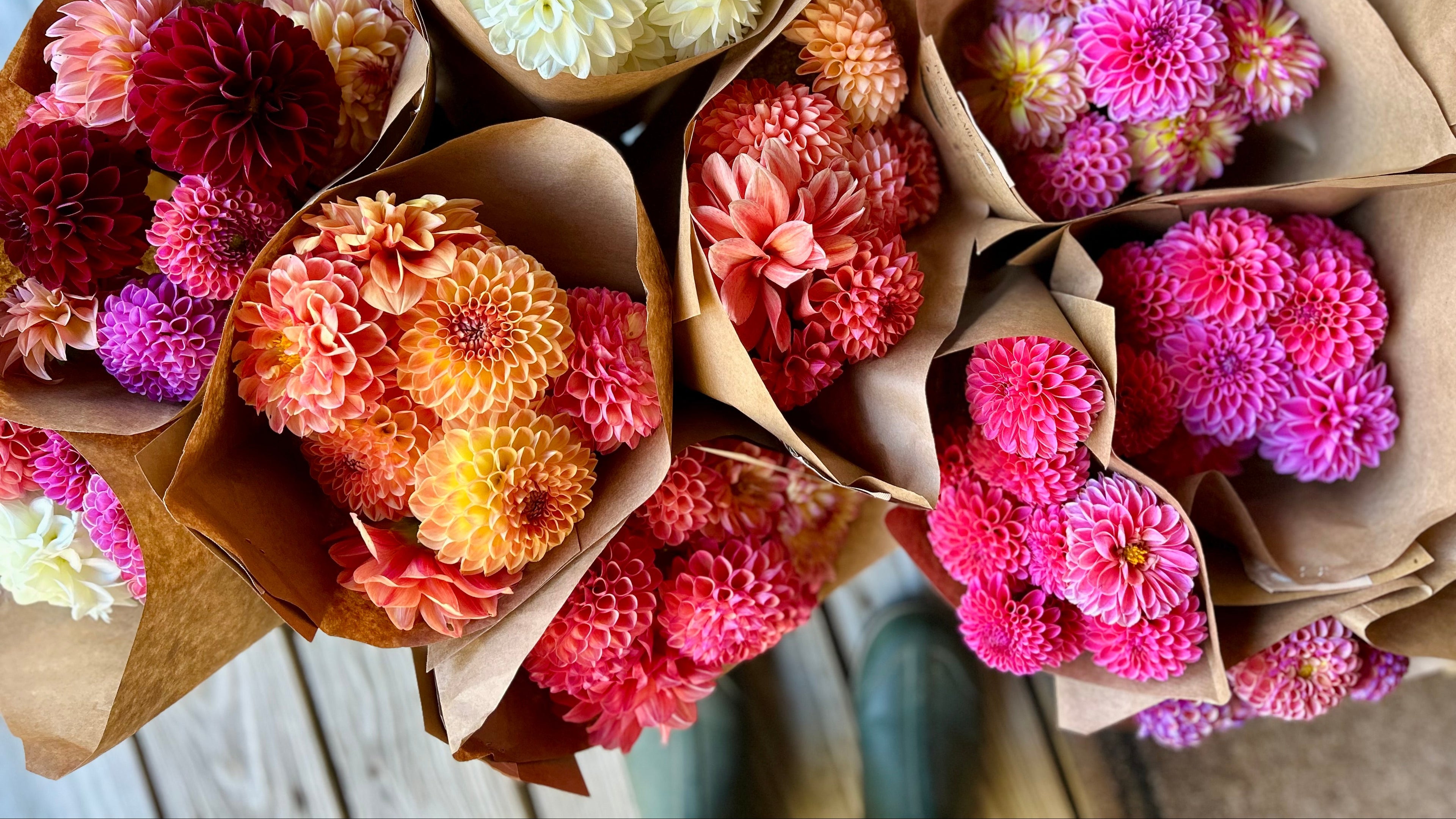 Bouquets of colorful flowers in brown paper packaging on a wooden surface