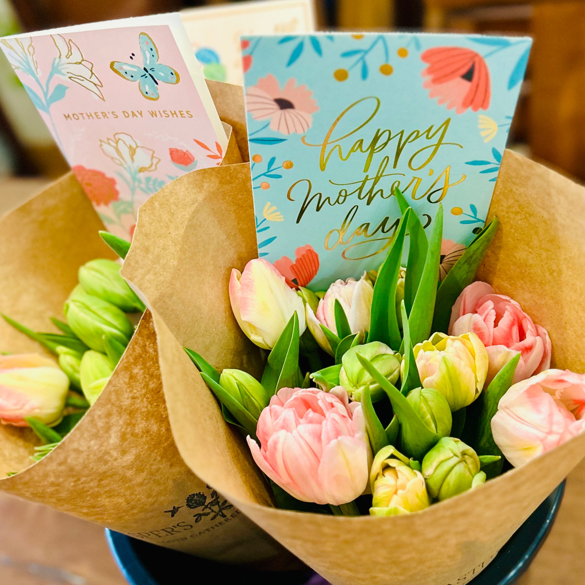 Bouquet of flowers with 'Happy Mother's Day' cards on a wooden surface