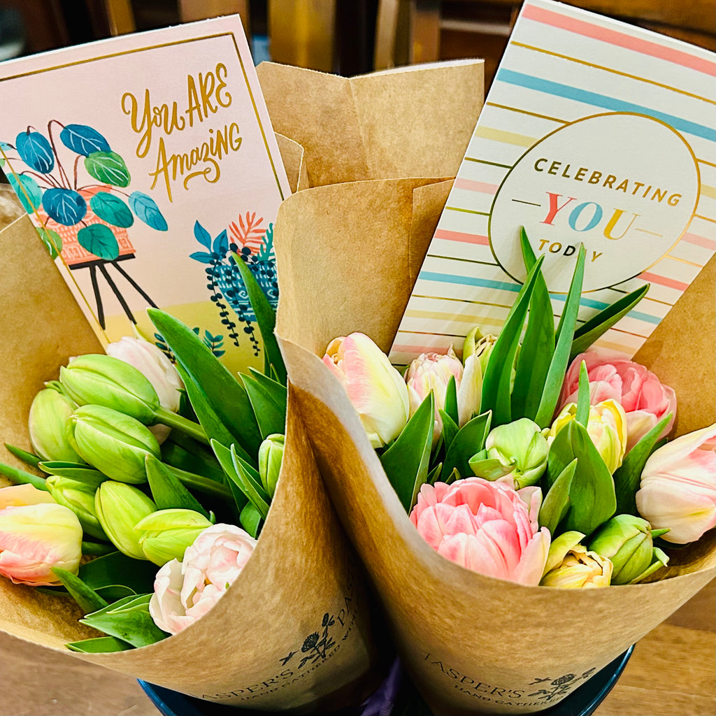 Two bouquets of flowers with matching cards on a wooden surface